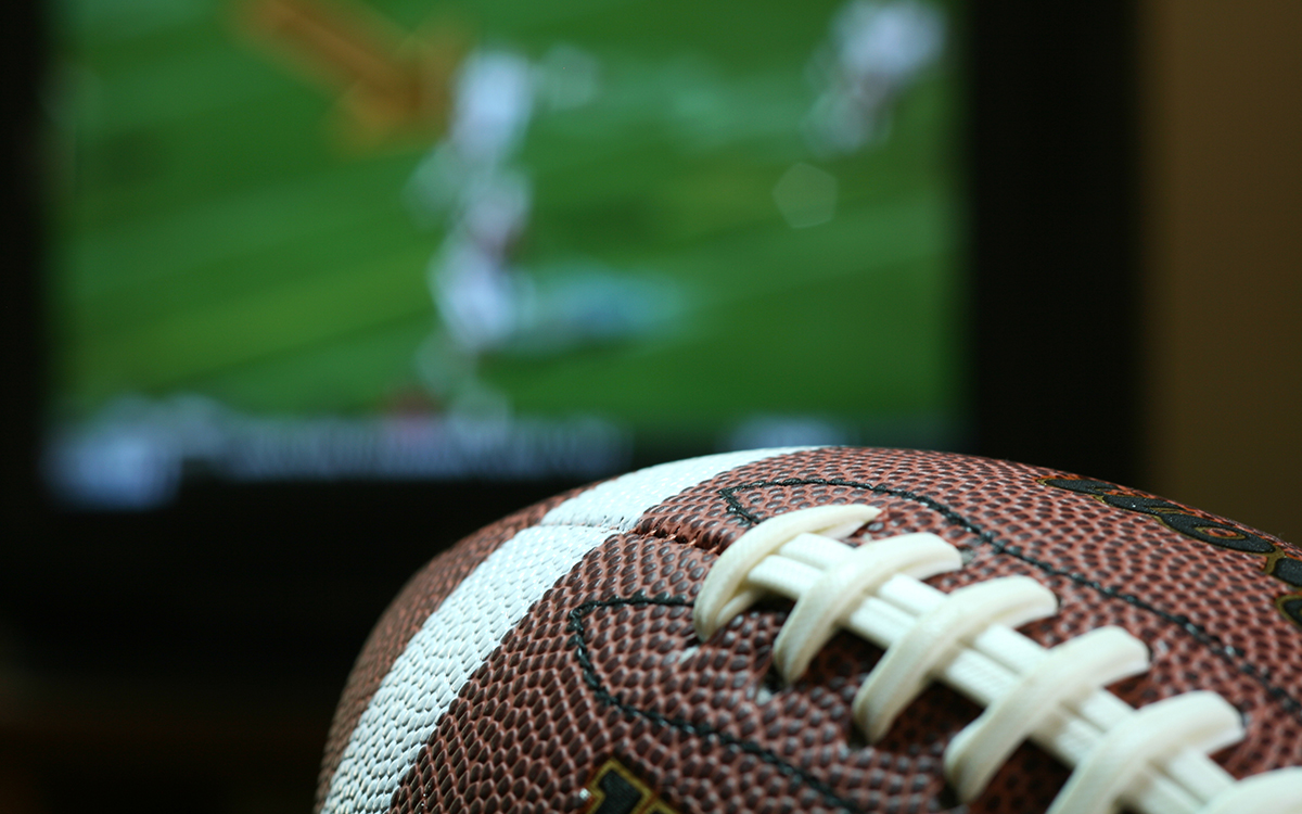 Football in front of TV displaying football game.