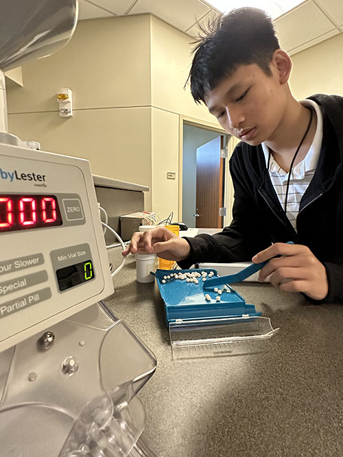 Student works with pill counter at 2023 KU Pharmacy Camp.