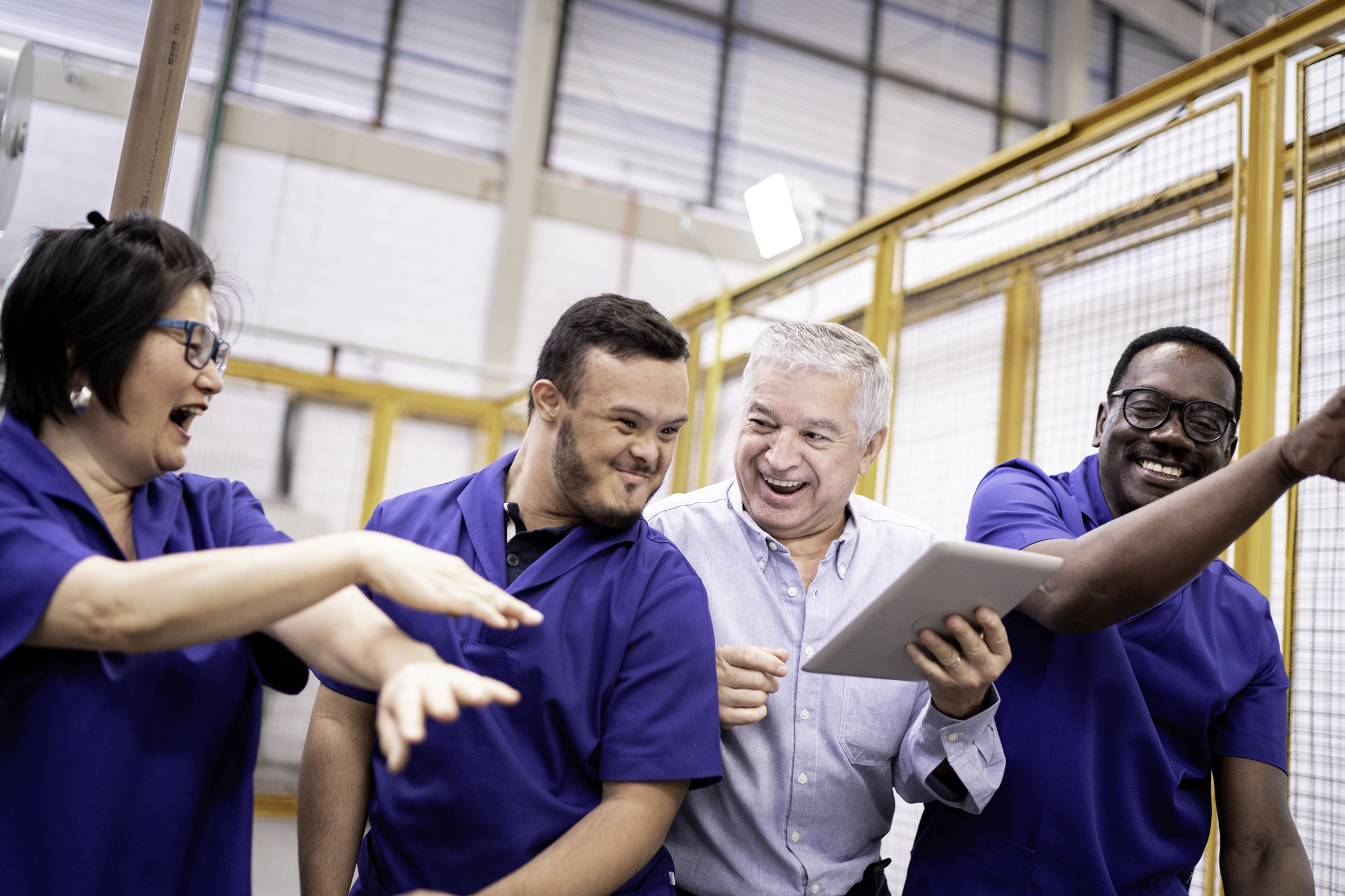 people are laughing good-naturedly in a workplace where all of the individuals are on a team in a warehouse and wearing blue shirts