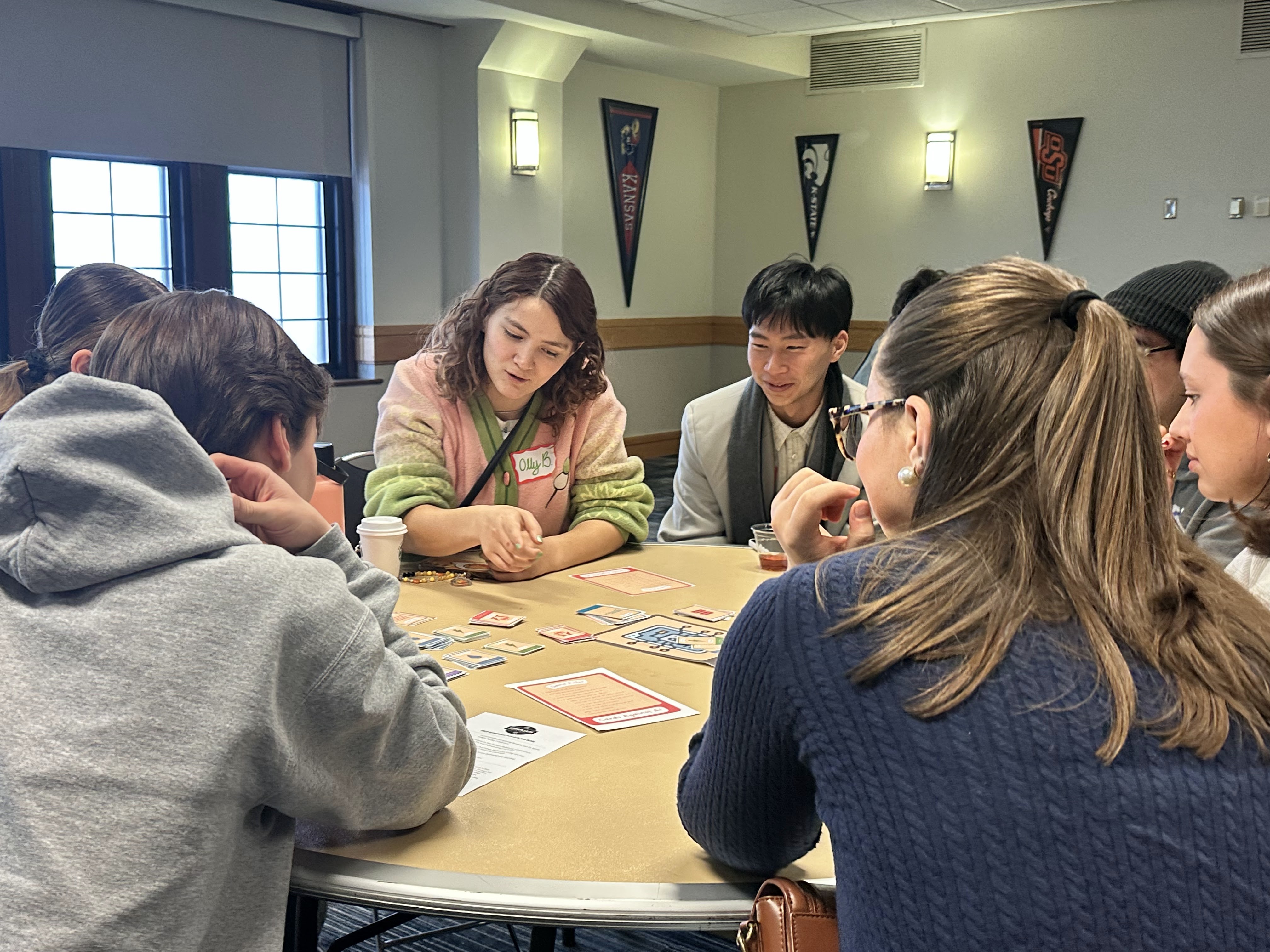 Students seated at round table discuss game 