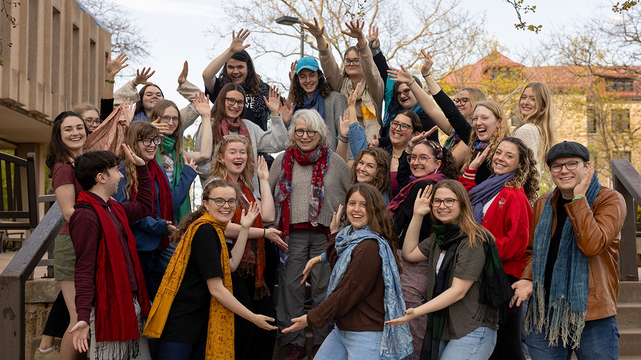 Group of students surround professor and pose