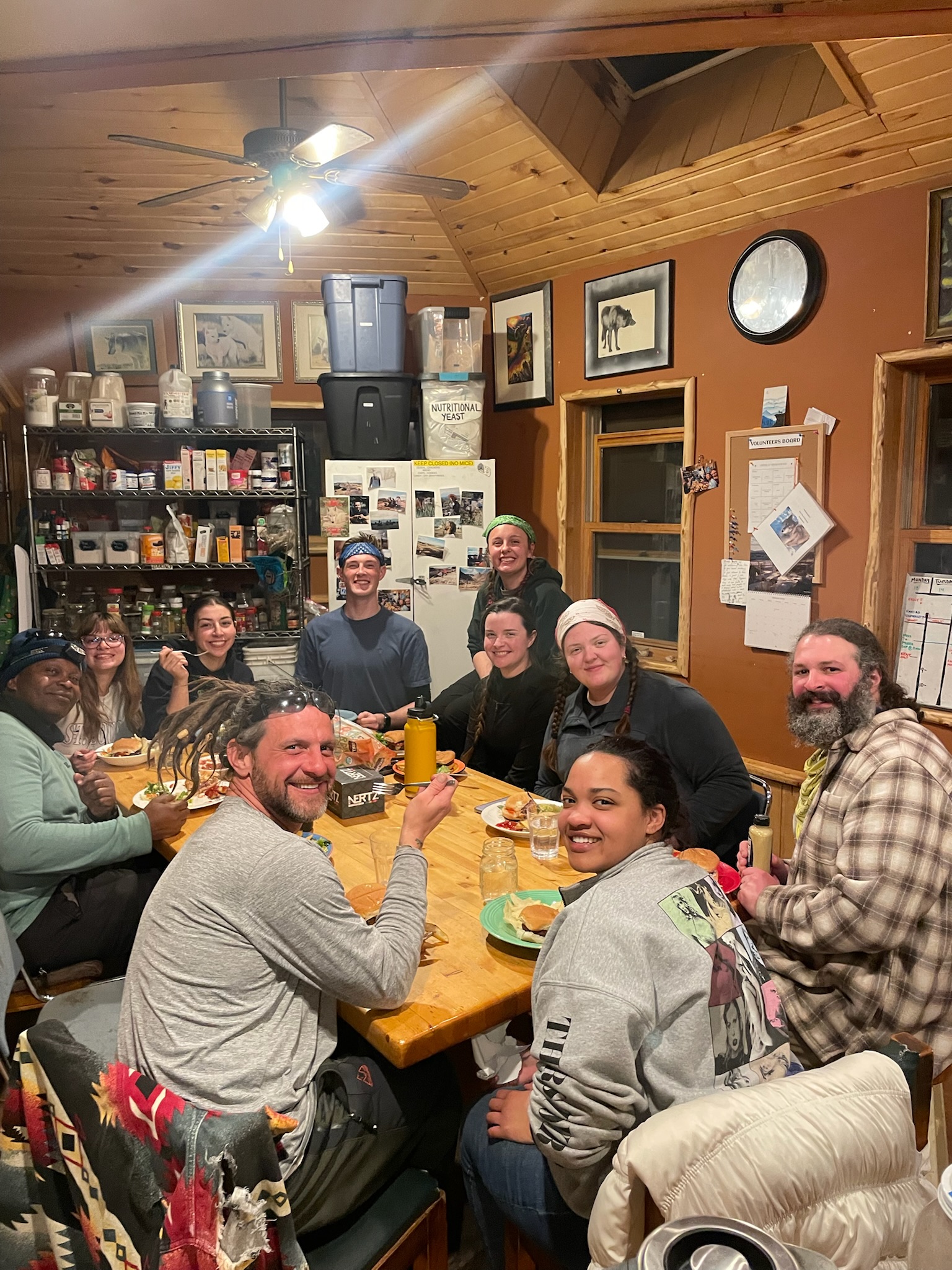 AB students and Mission:Wolf staff sitting around a table eating dinner, smiling