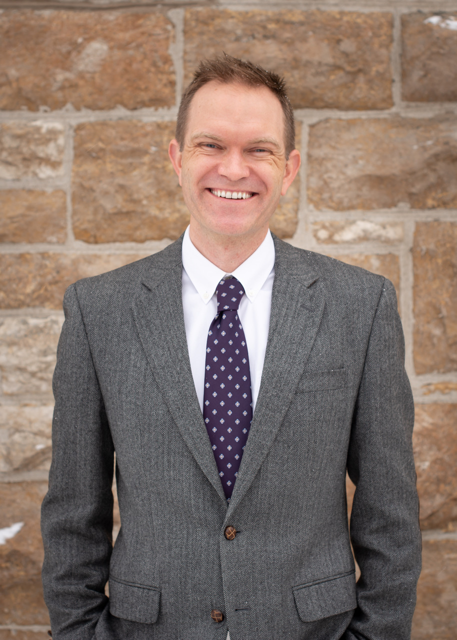 a man standing in a suit and smiling