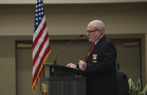 KLETC director Darin Beck speaks from podium with American flag in view.