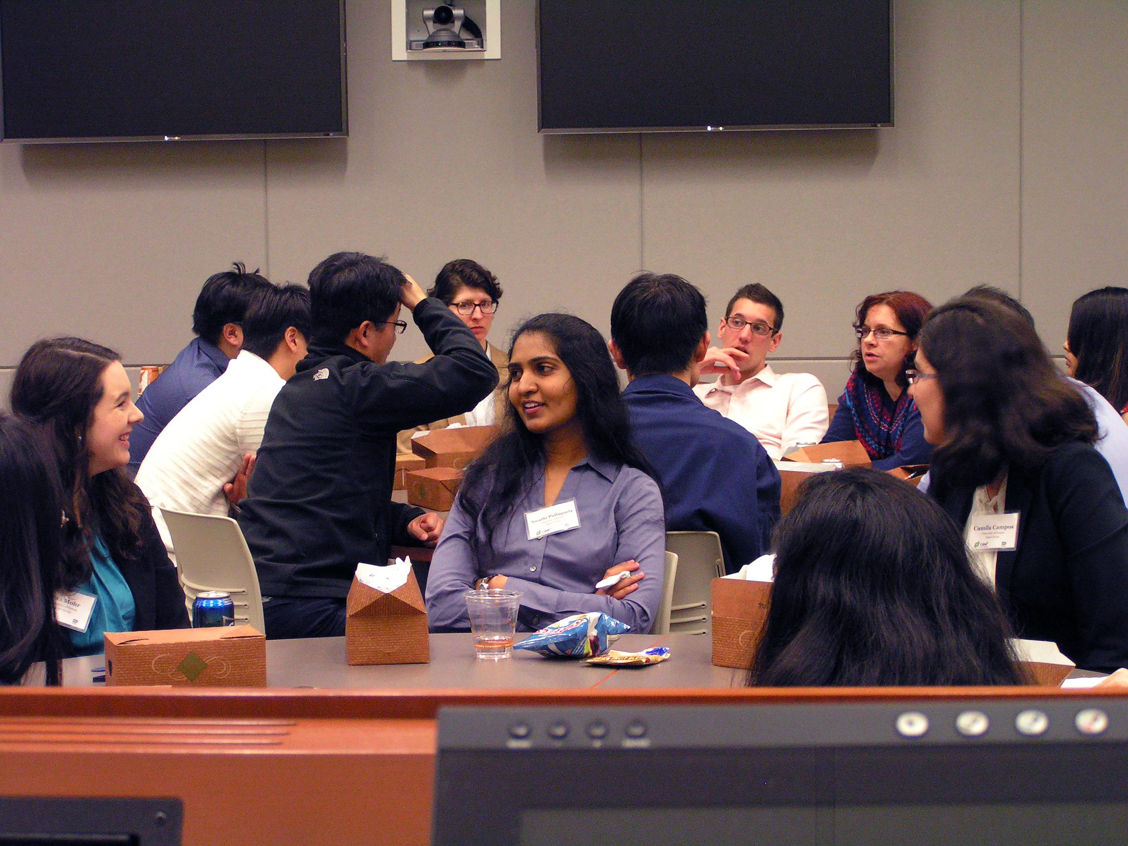 Several people sitting around tables, engaged in conversation.