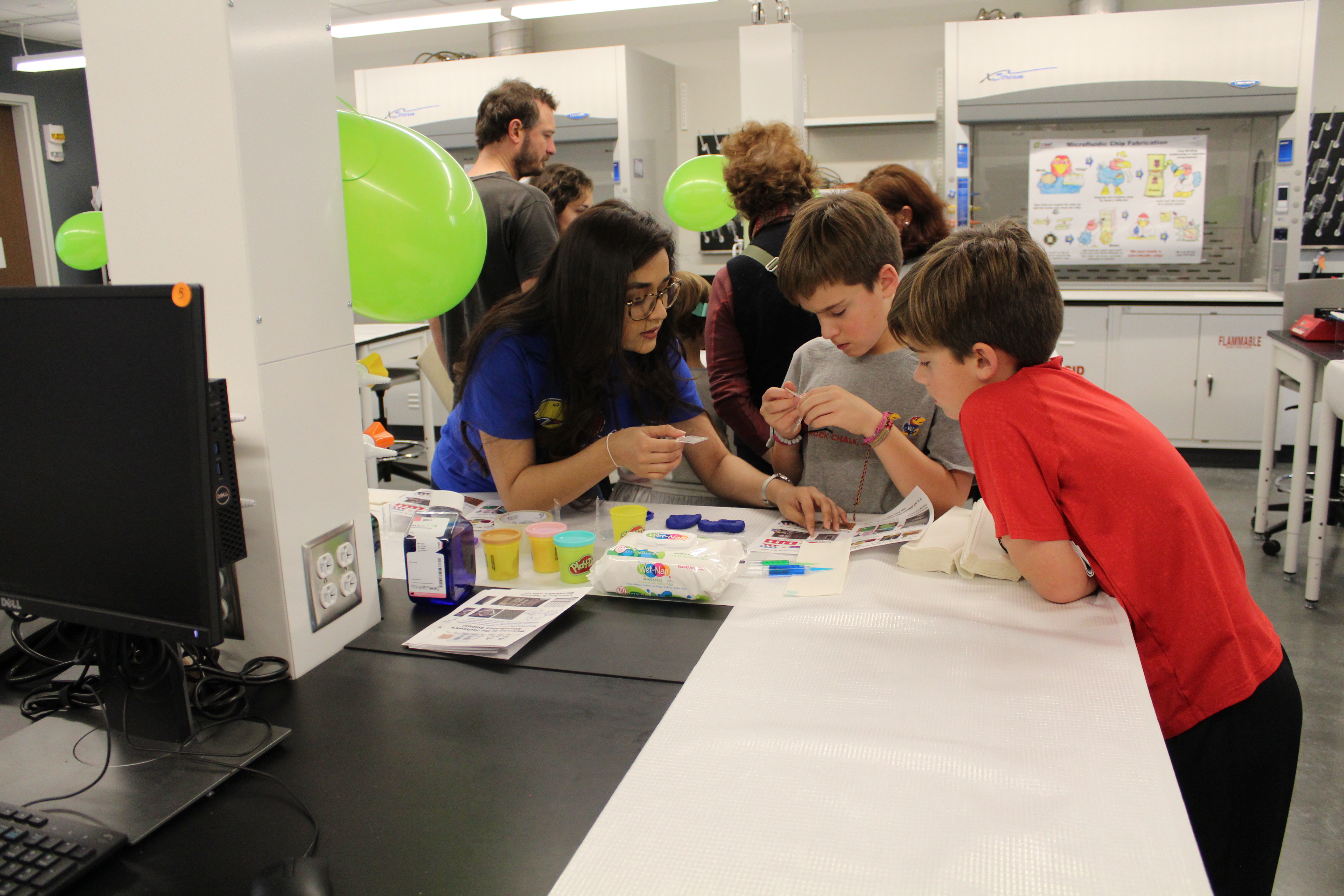 Adult demonstrating a craft project to two children.