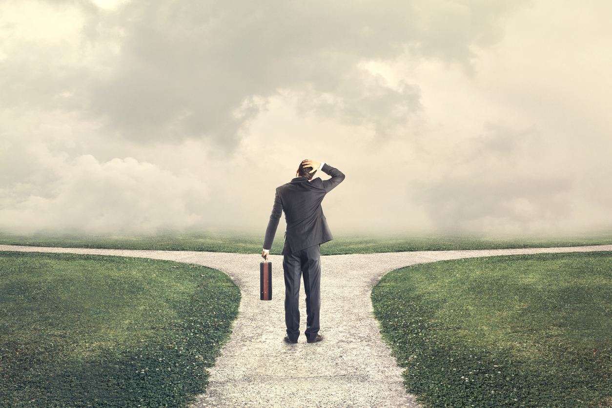 Illustration of a man in a suit standing at a fork in the road