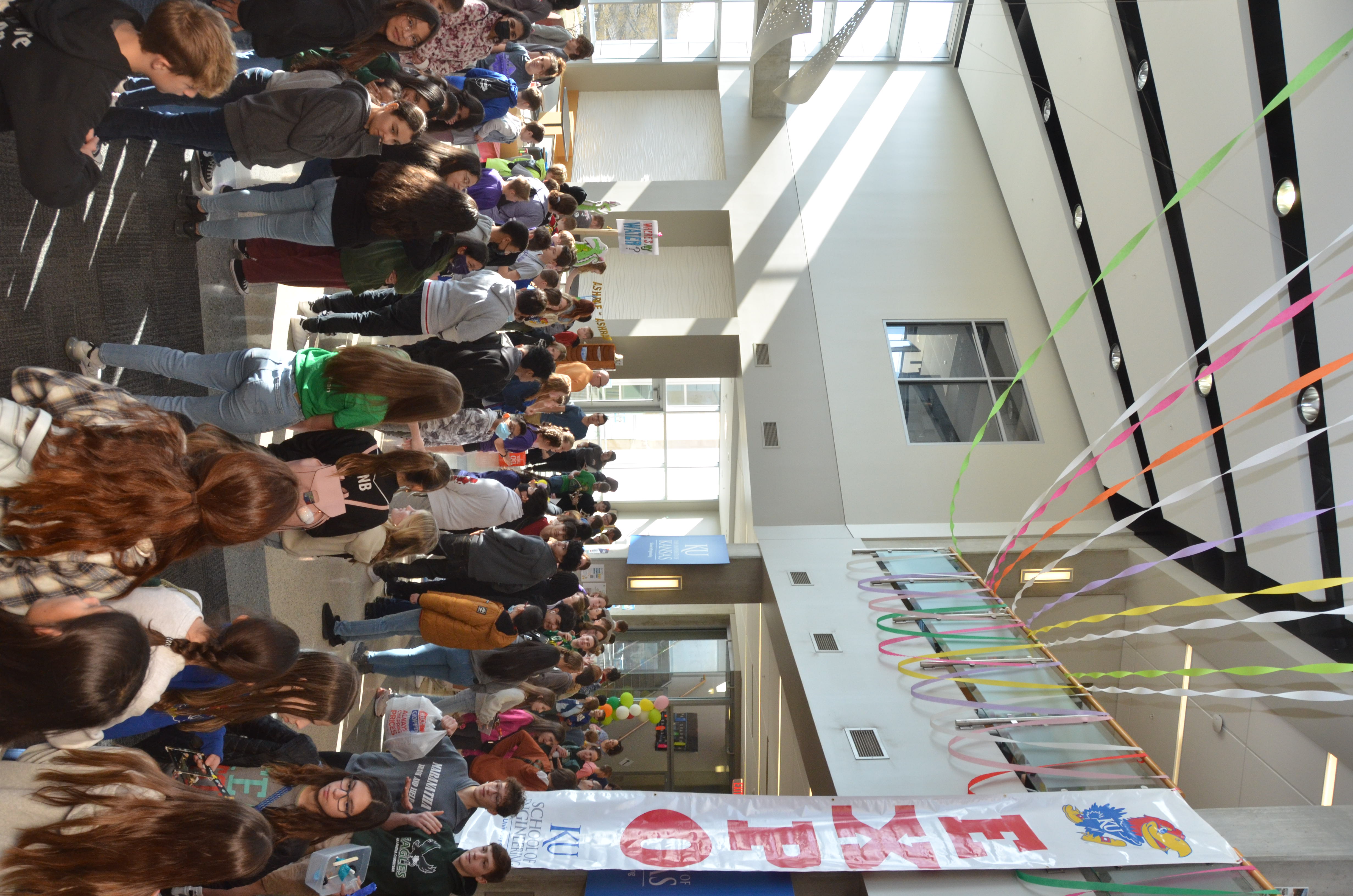 Students mill about atrium where a large banner hangs with "EXPO" and Jayhawk image.